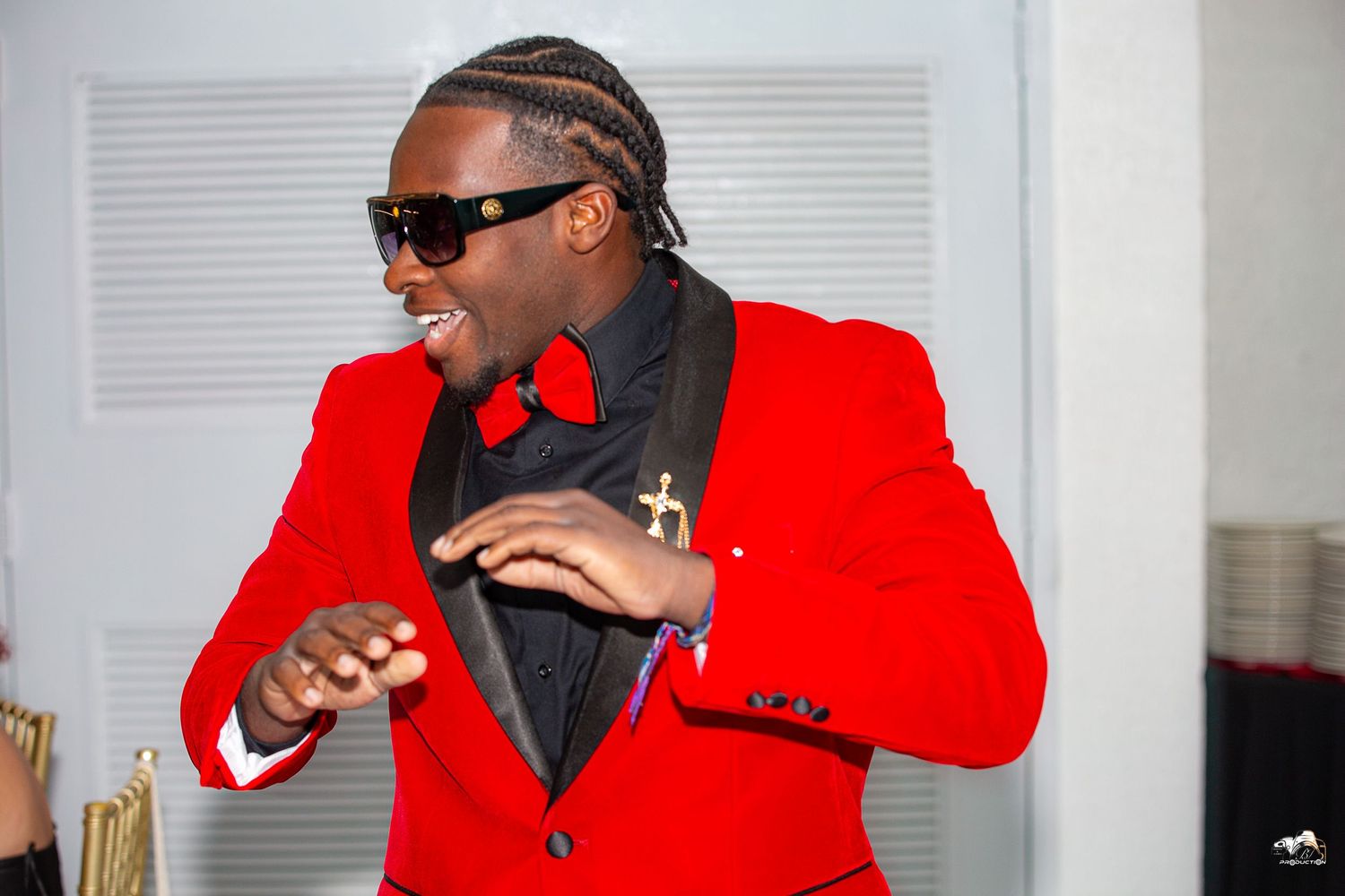 Performer in red blazer and sunglasses dancing energetically.