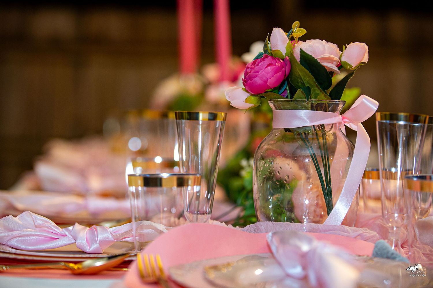 Elegant wedding table setting with pink floral centerpiece, champagne glasses and place settings.
