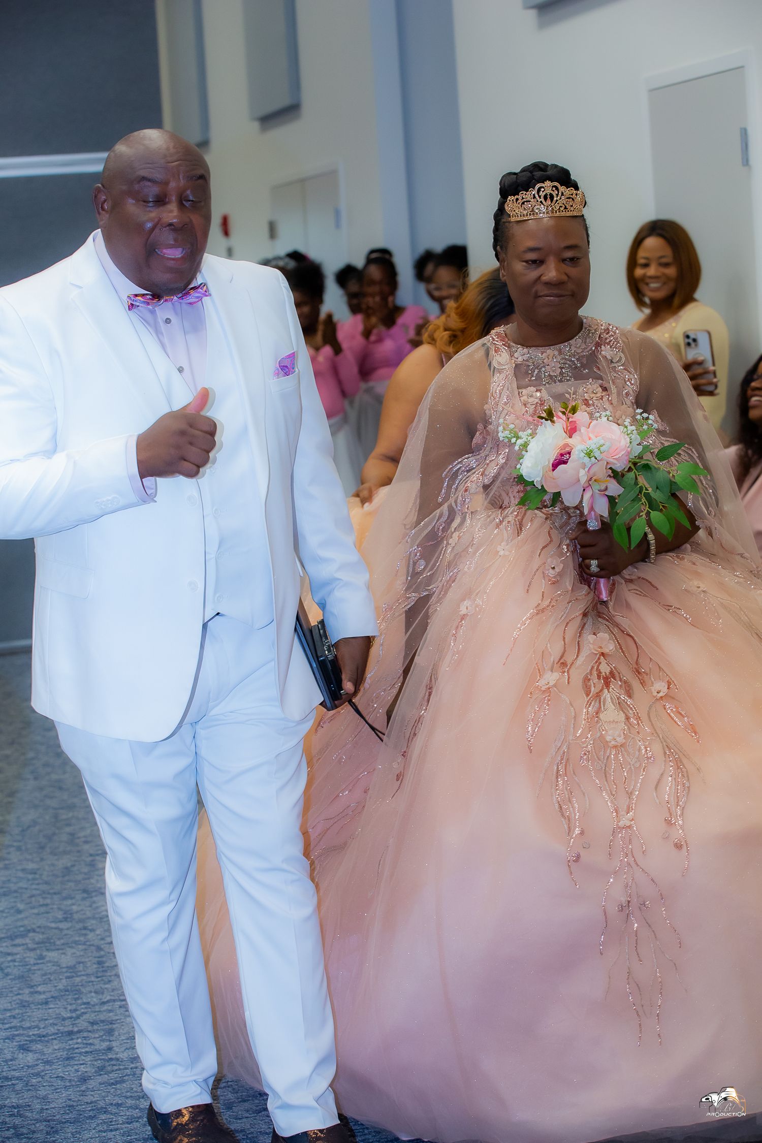 A couple in white and pink formal attire walking together at an event.