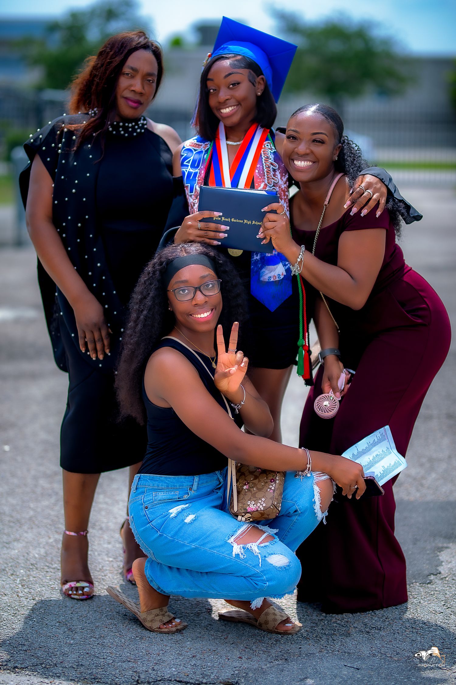 Graduation celebration photo with proud group posing outdoors with diploma and medals.