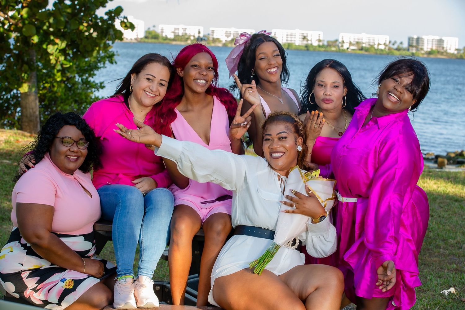 A group in pink outfits enjoys a waterfront picnic gathering.