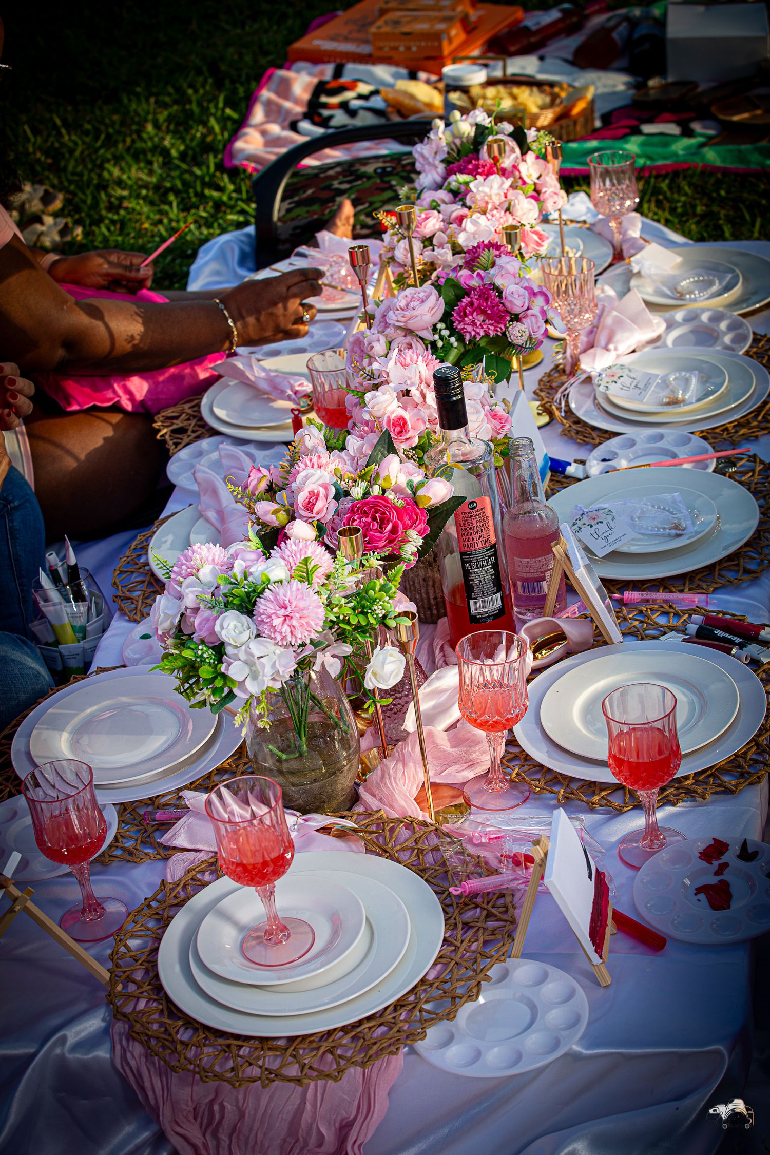 An elegant table setting with pink flowers, crystal glasses and white plates.