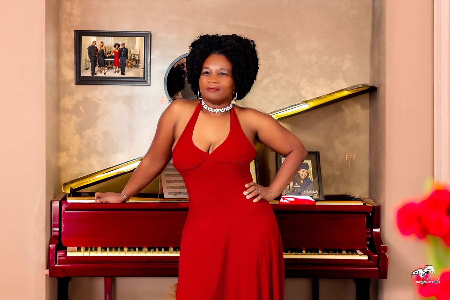 A performer in a red dress poses elegantly beside a grand piano.