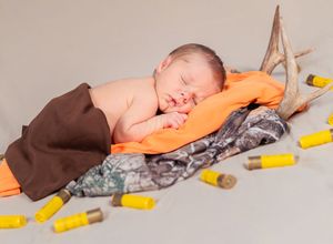 A sleeping baby lies on a soft surface next to yellow toy blocks arranged in a line.