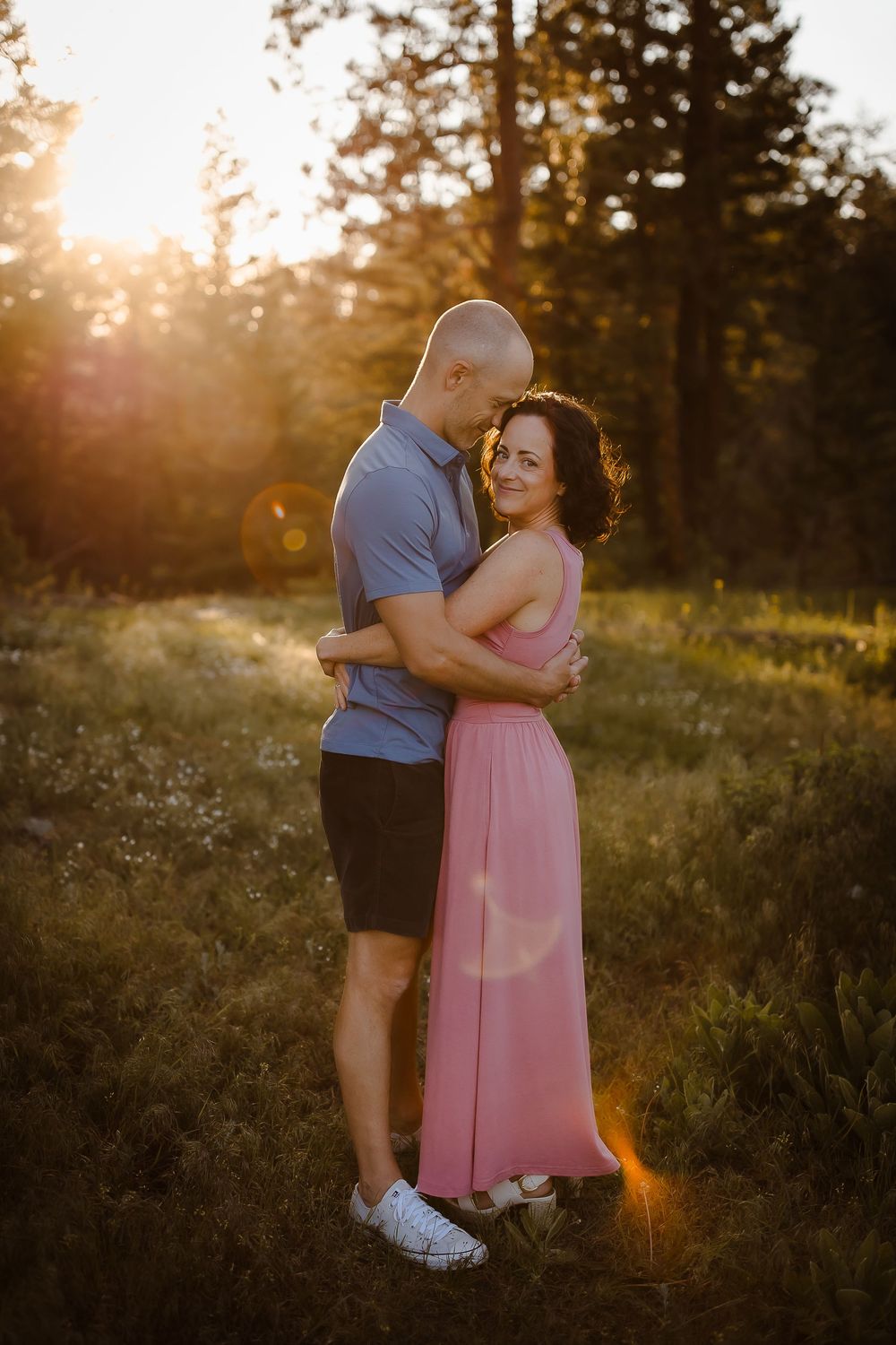 Two children embrace and smile candidly in Denver field with golden light behind them