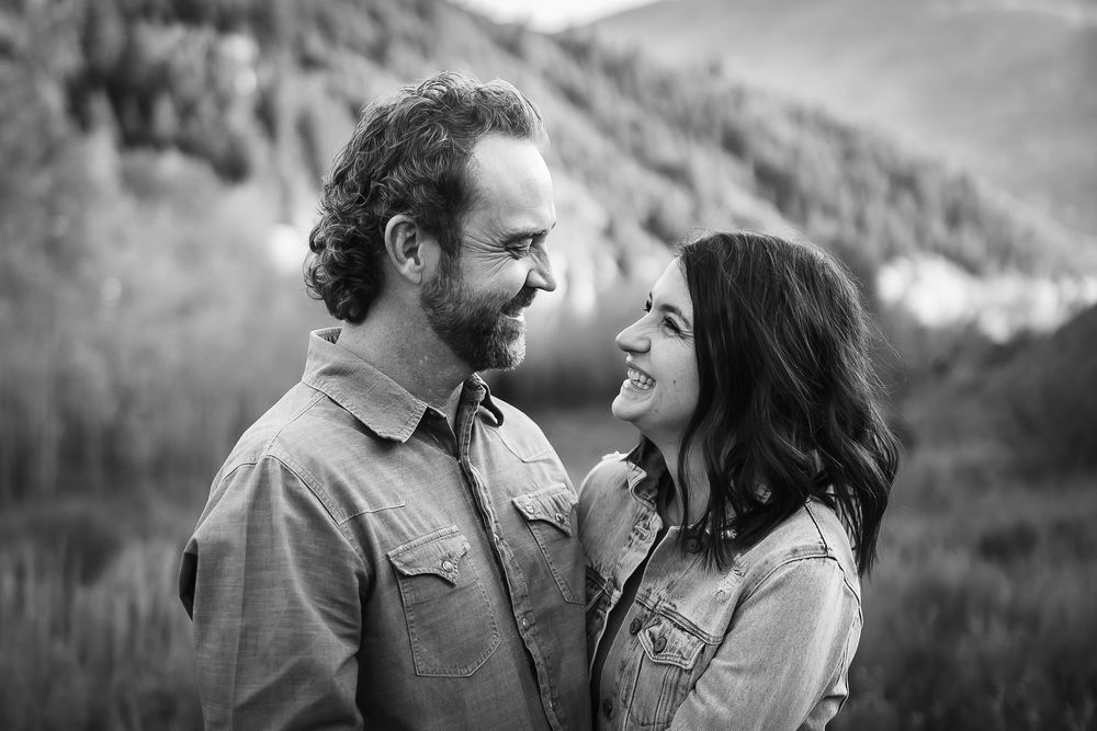 A black and white photograph of a couple laughing and smiling together in the Colorado mountains