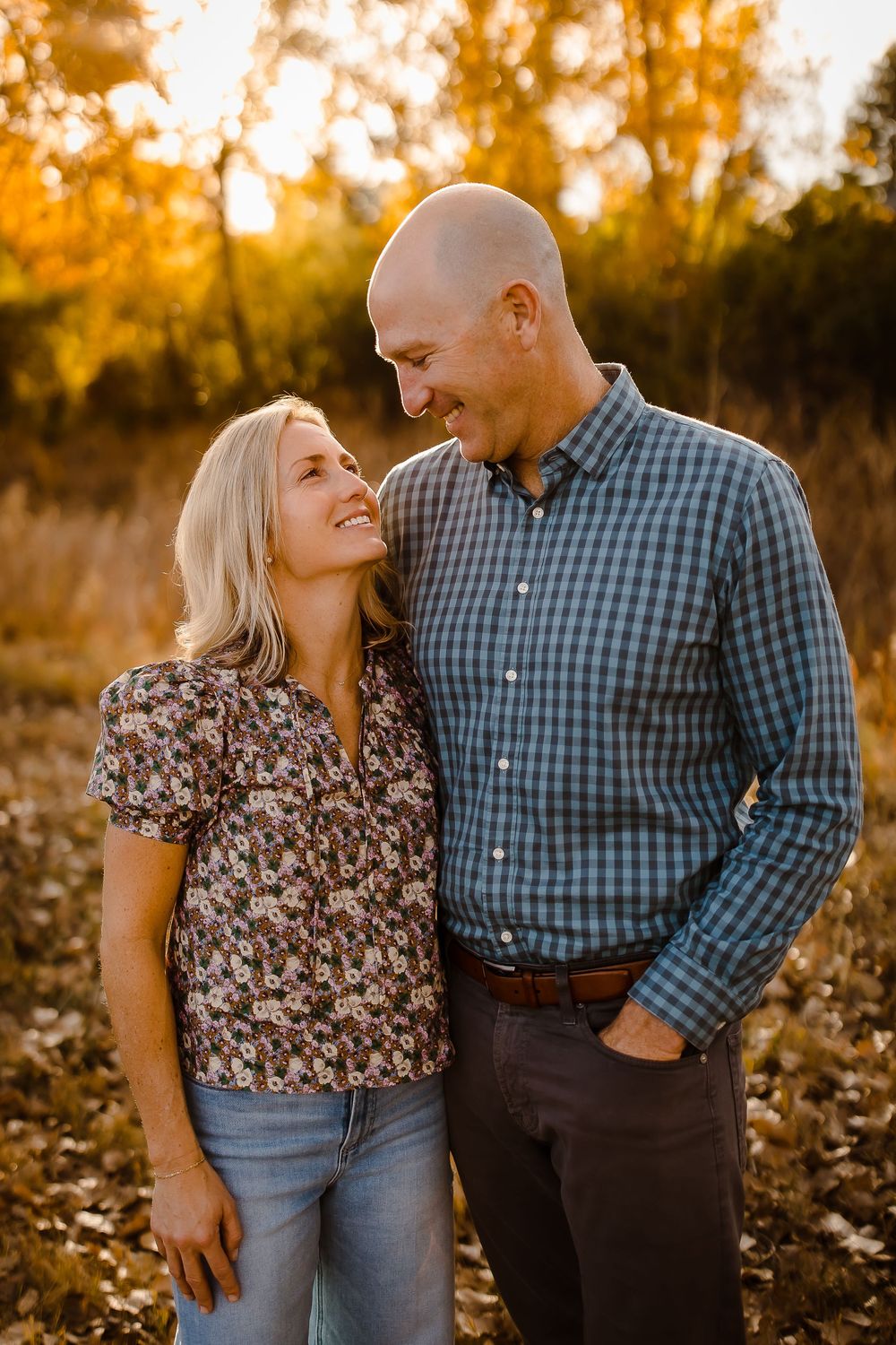 Couple smiling happily at one another in front of Denver Colorado yellow fall foliage