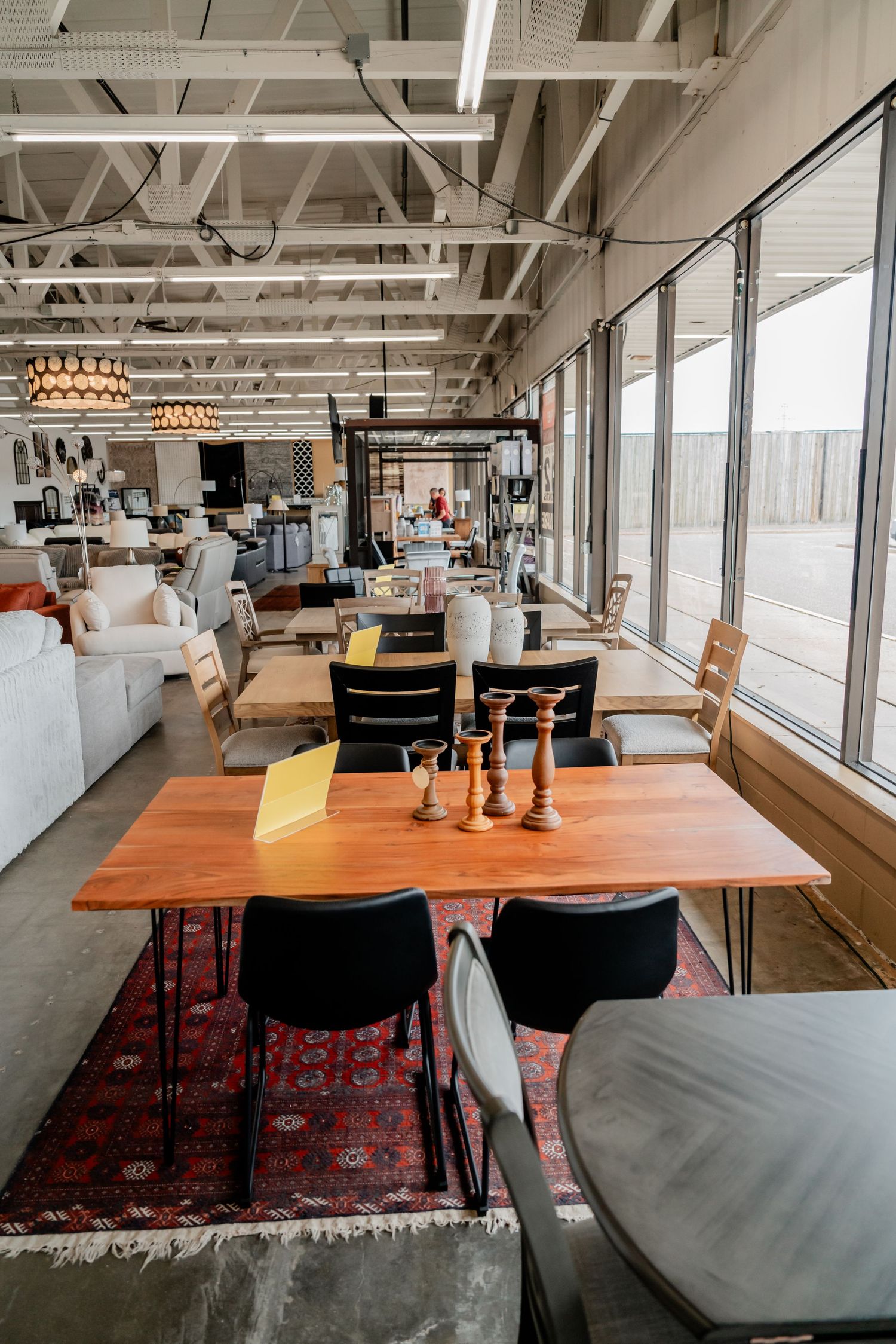 Modern industrial restaurant interior with wooden tables and large windows.