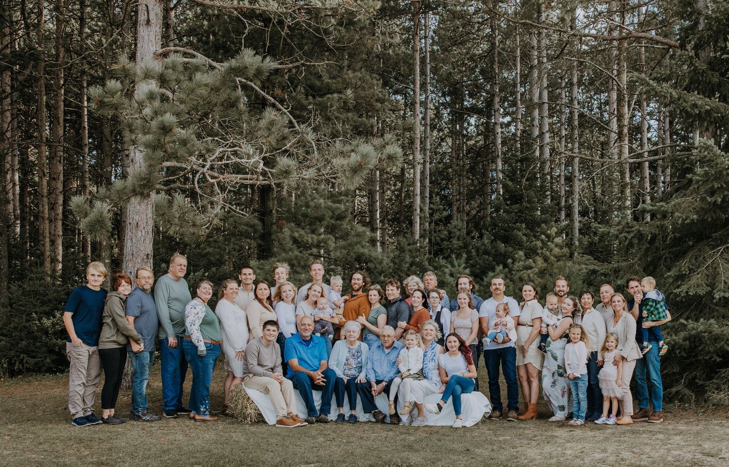 Group portrait of people and dogs standing together outdoors in late afternoon sunlight.