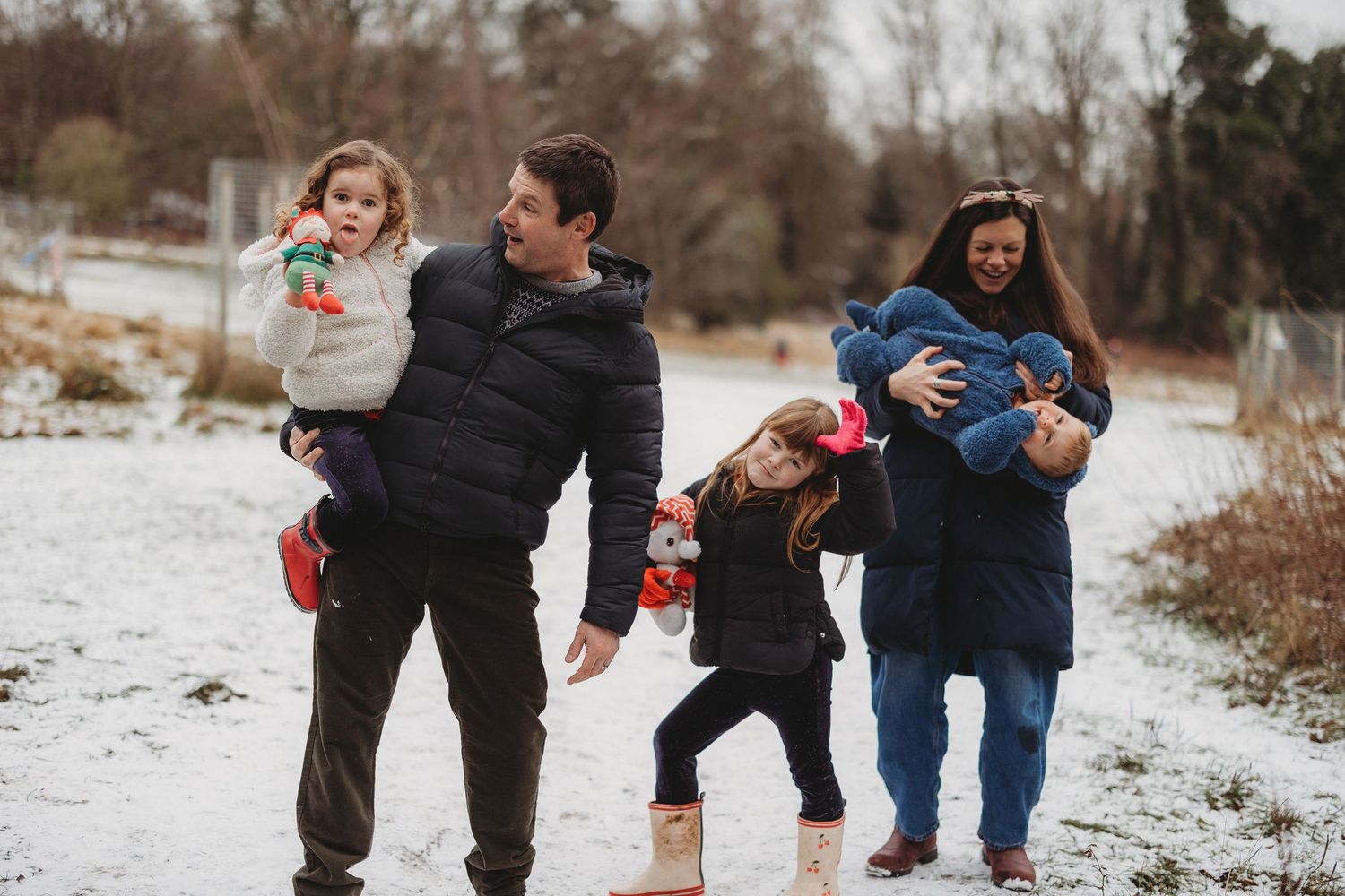 A family plays together in the snow on a winter day, throwing snowballs and enjoying outdoor fun.