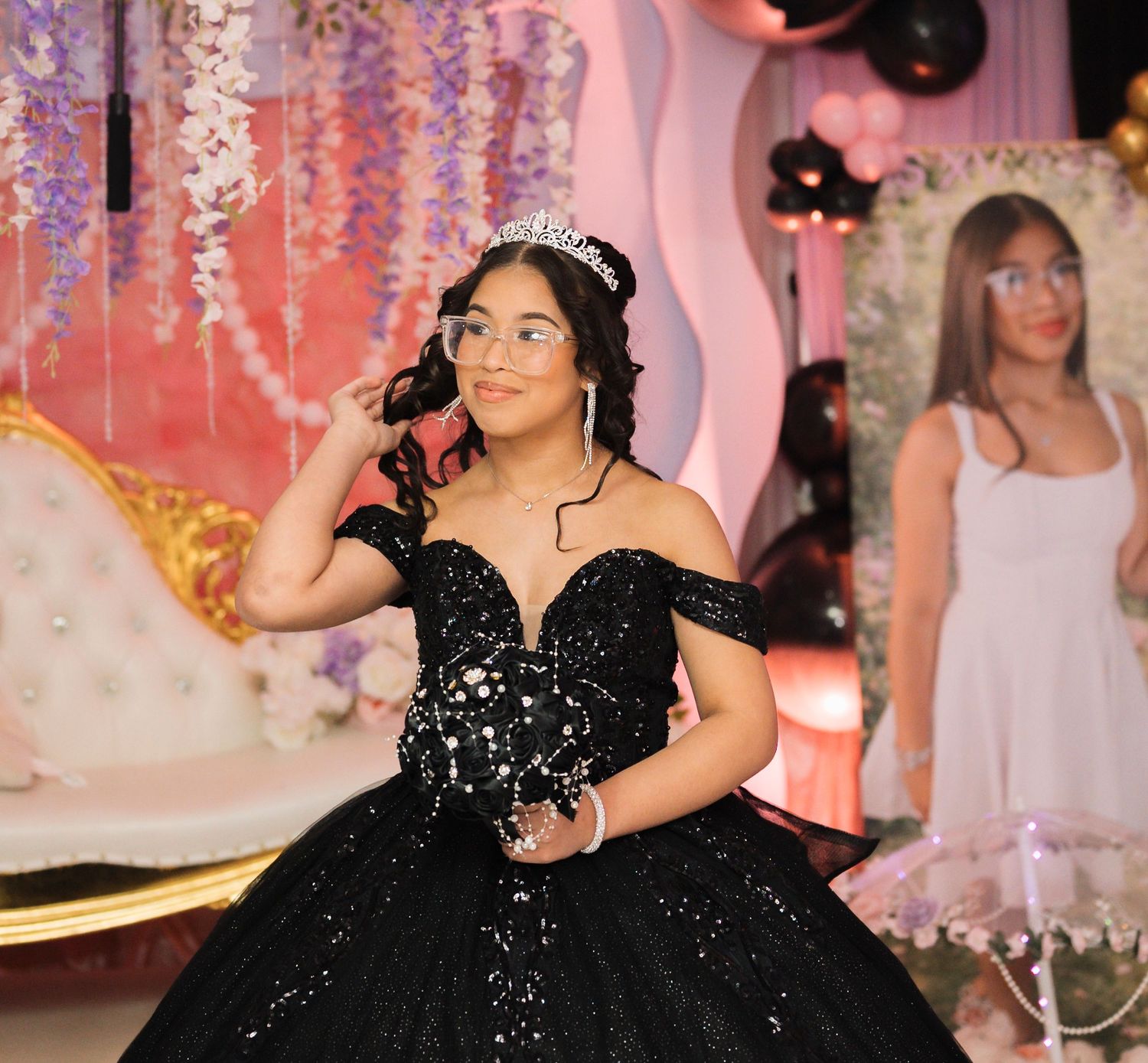 Young woman in black sequin off-shoulder ball gown wearing tiara at quinceañera celebration in Chicopee.