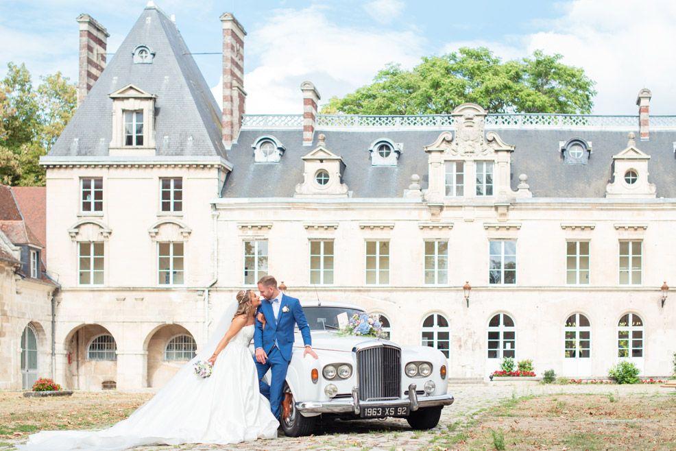 photo de mariage devant un beau bâtiment et une vieille voiture de collection