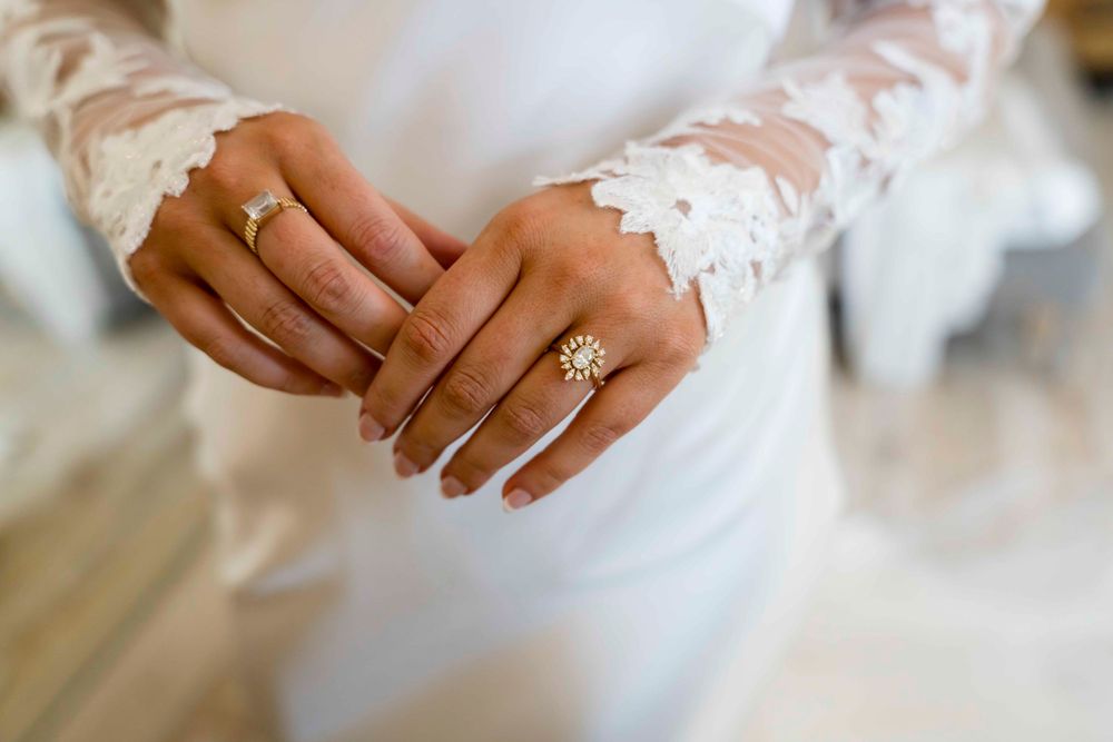 Close up of bride's hands showing lace sleeve details and engagement ring.