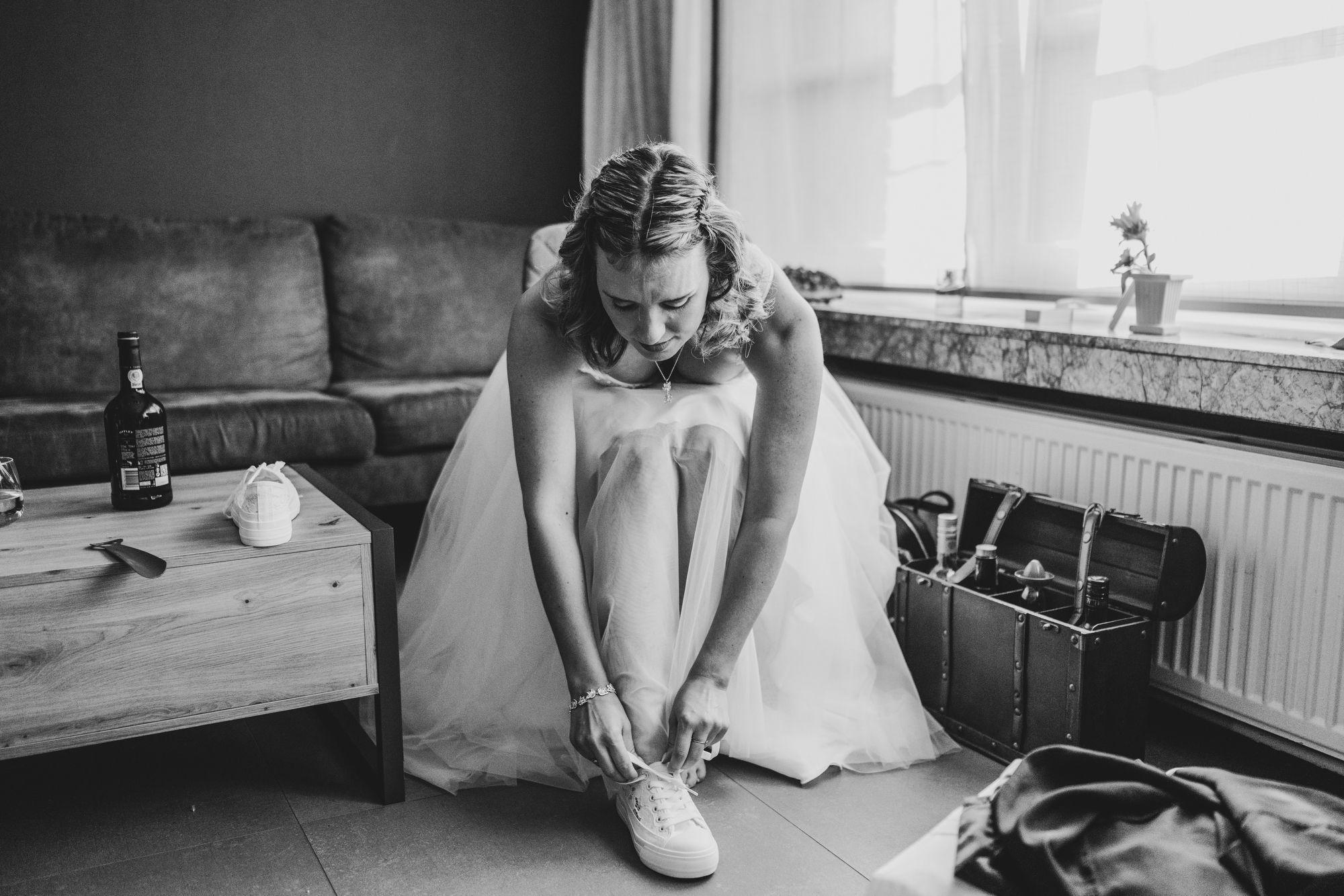Bruid strikt haar sneakers voor de trouwdag, spontaan en puur vastgelegd door huwelijksfotograaf Bart Boodts Photography.