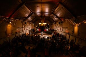 Romantische eerste dans van een bruidspaar in een sfeervol verlichte feestzaal El Dorado, omringd door gasten en fonkelende lichtslingers