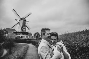 Lachend bruidspaar bij molen in Willemstad, Nederland, vastgelegd door Bart Boodts, huwelijksfotograaf met natuurlijke stijl