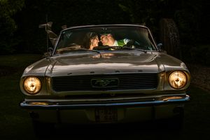 Romantisch huwelijksportret in een klassieke Ford Mustang bij zonsondergang in Aalst, vastgelegd door Bart Boodts Photography