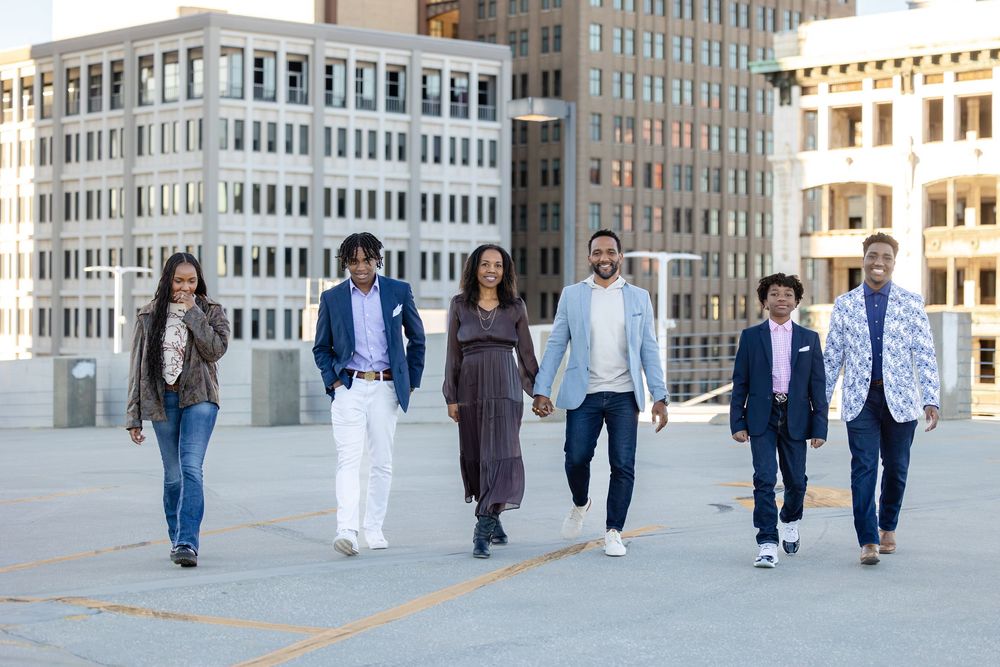 Group walking together along urban sidewalk with modern office buildings in background.
