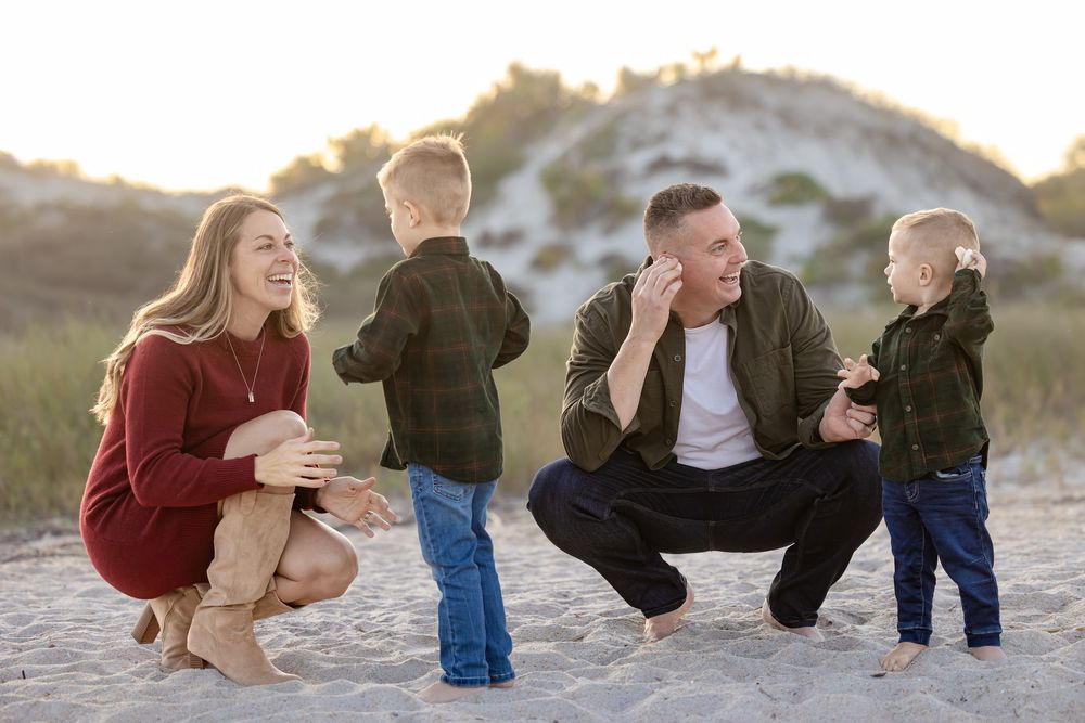 Family members sitting together on beach sand during golden hour.
