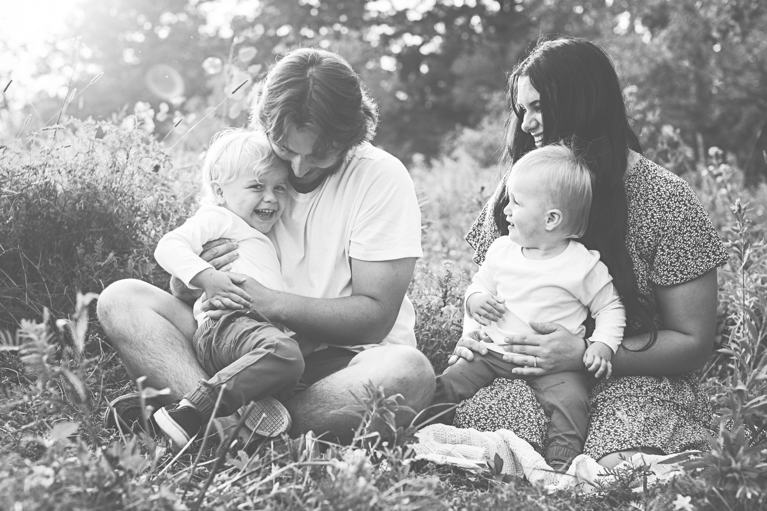 A black and white photo sequence shows a parent and child reading together while sitting outdoors in the grass.