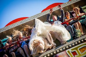 Wedding couple poses under ornate archway with dramatic lighting and red floral decoration. fairground wedding at the old vicarige Dorset