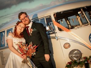 A vintage VW camper is the backdrop for a wedding couple at sunset with warm autumn-coloured florals. Shot at Notley Tythe Barn in Oxford