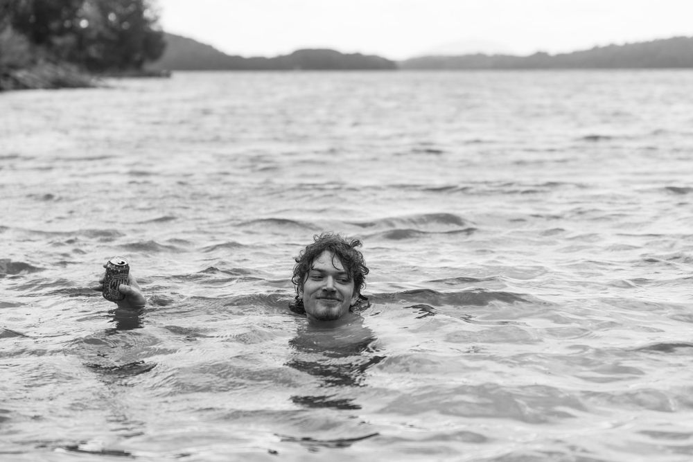 Black and white photo of someone swimming in a calm lake.
