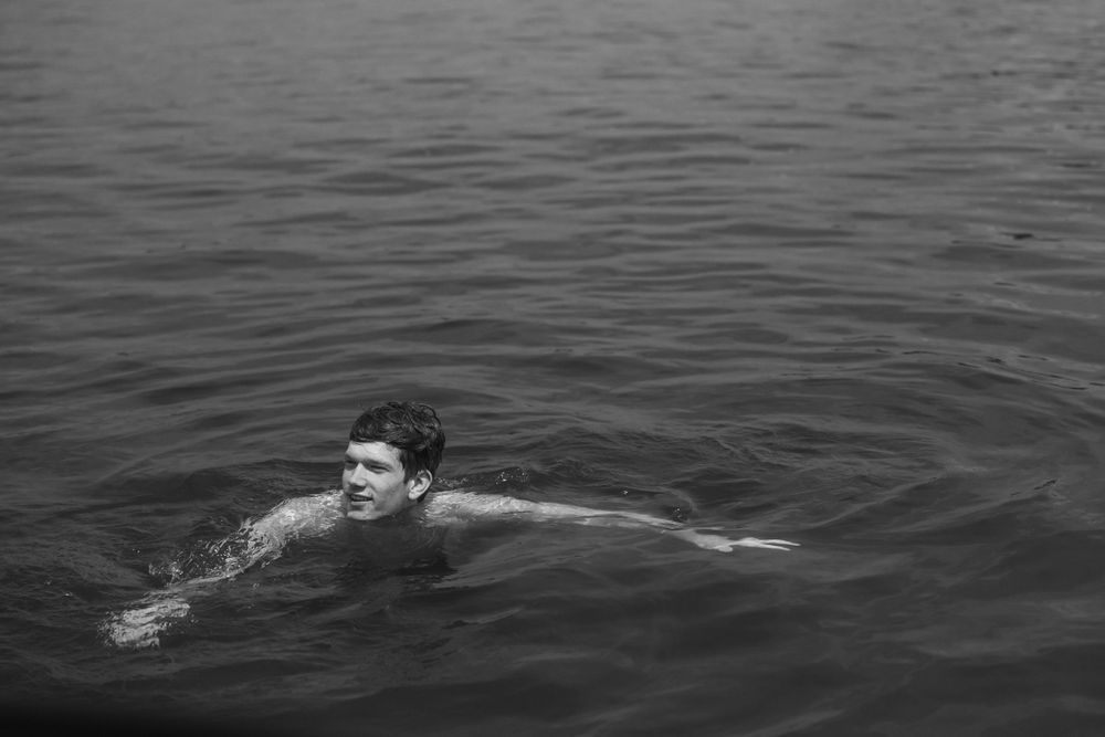 Person swimming in dark waters captured in black and white photography.