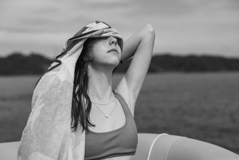 Person drying off with towel by lake in black and white photo.