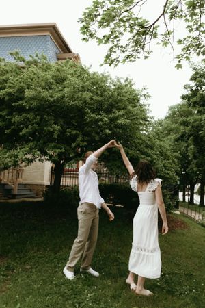 Couple dances in a backyard garden with trees in the background.
