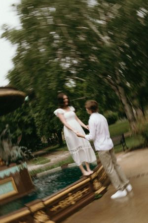 Motion-blurred photo of couple playing near a garden fountain.