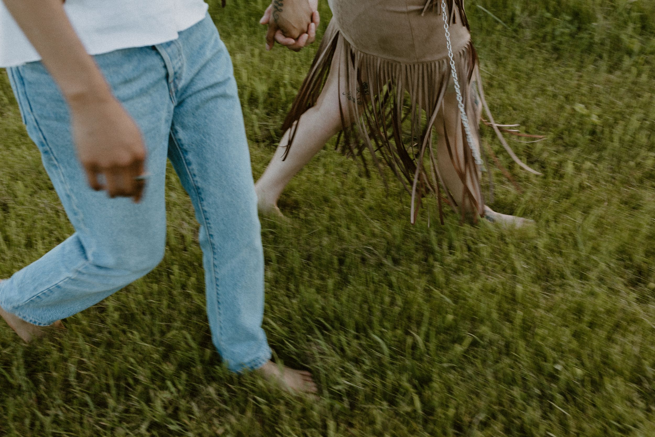 Playful movement captured in a candid shot showing feet and legs dancing in grass.