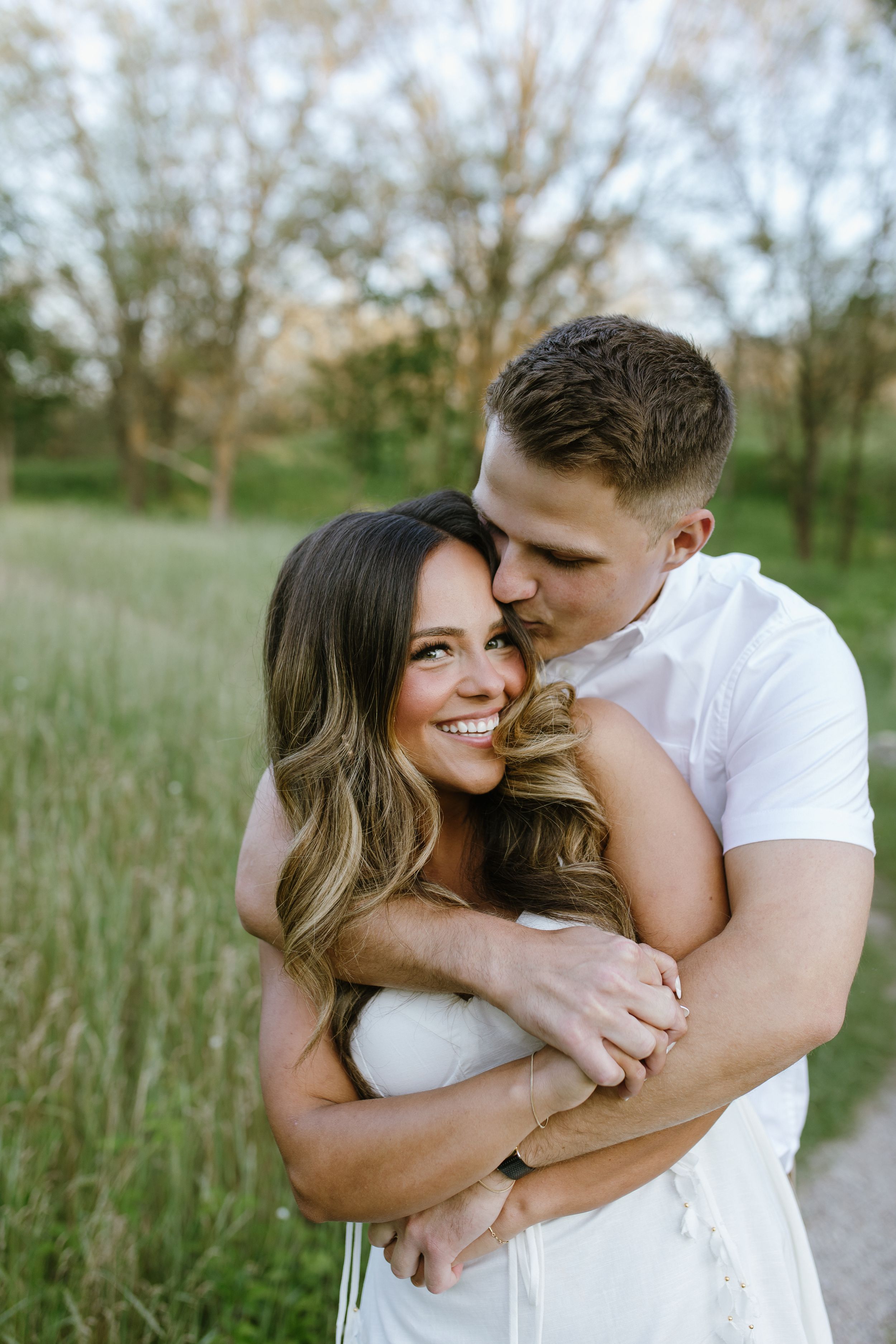 A romantic outdoor portrait of a couple embracing in a sunlit field.