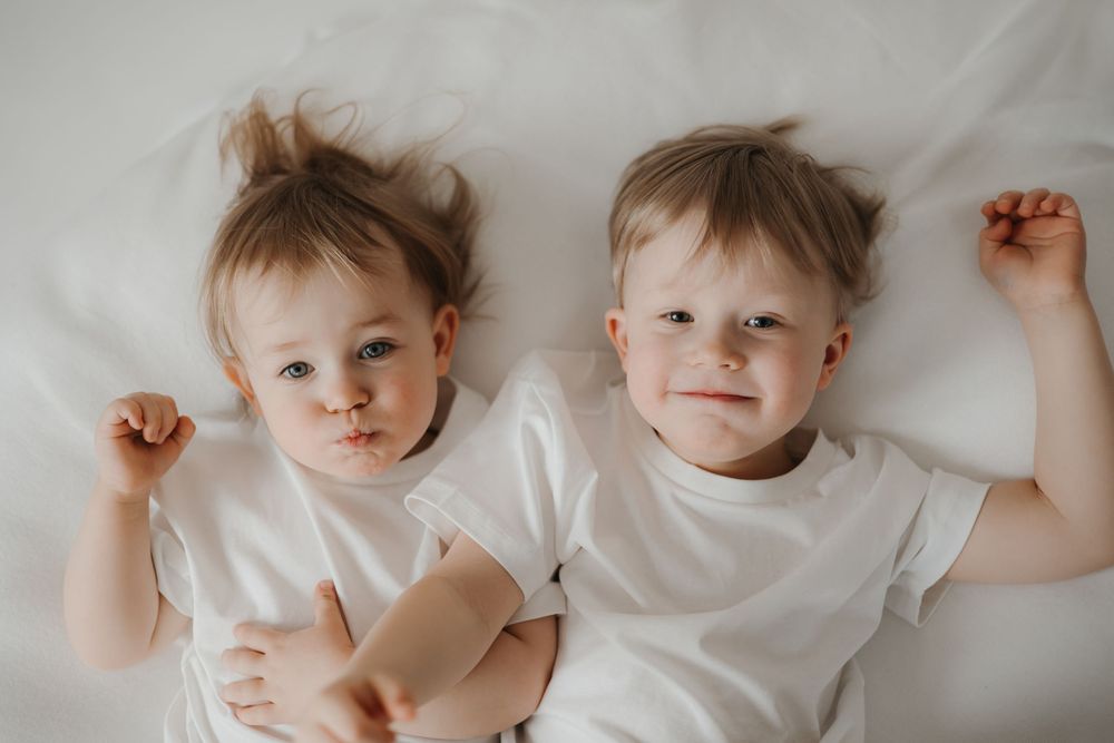 Children in white shirts lying on light background.