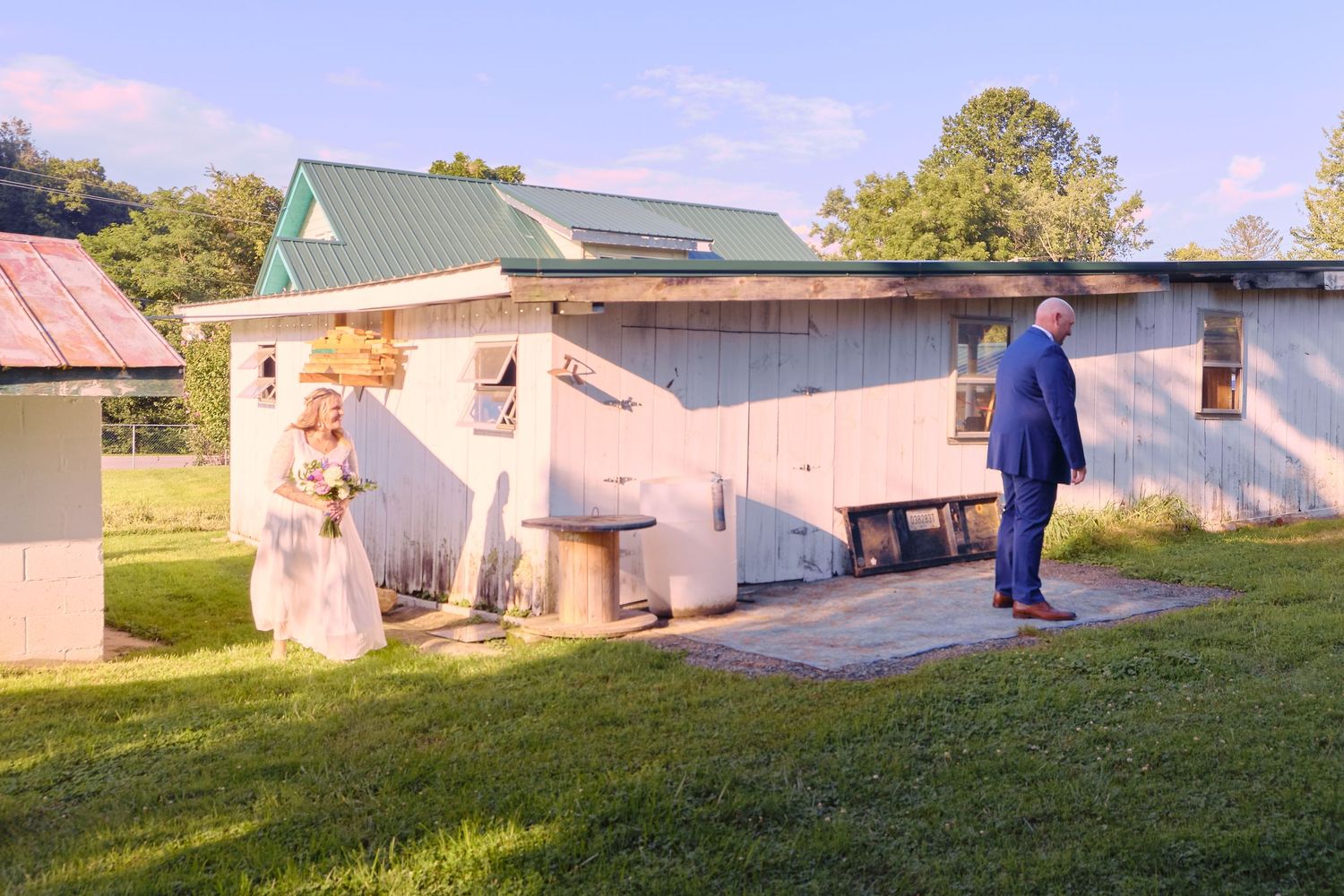 Panoramic sequence showing rural home renovation work with white exterior walls and green lawn under sunny sky.