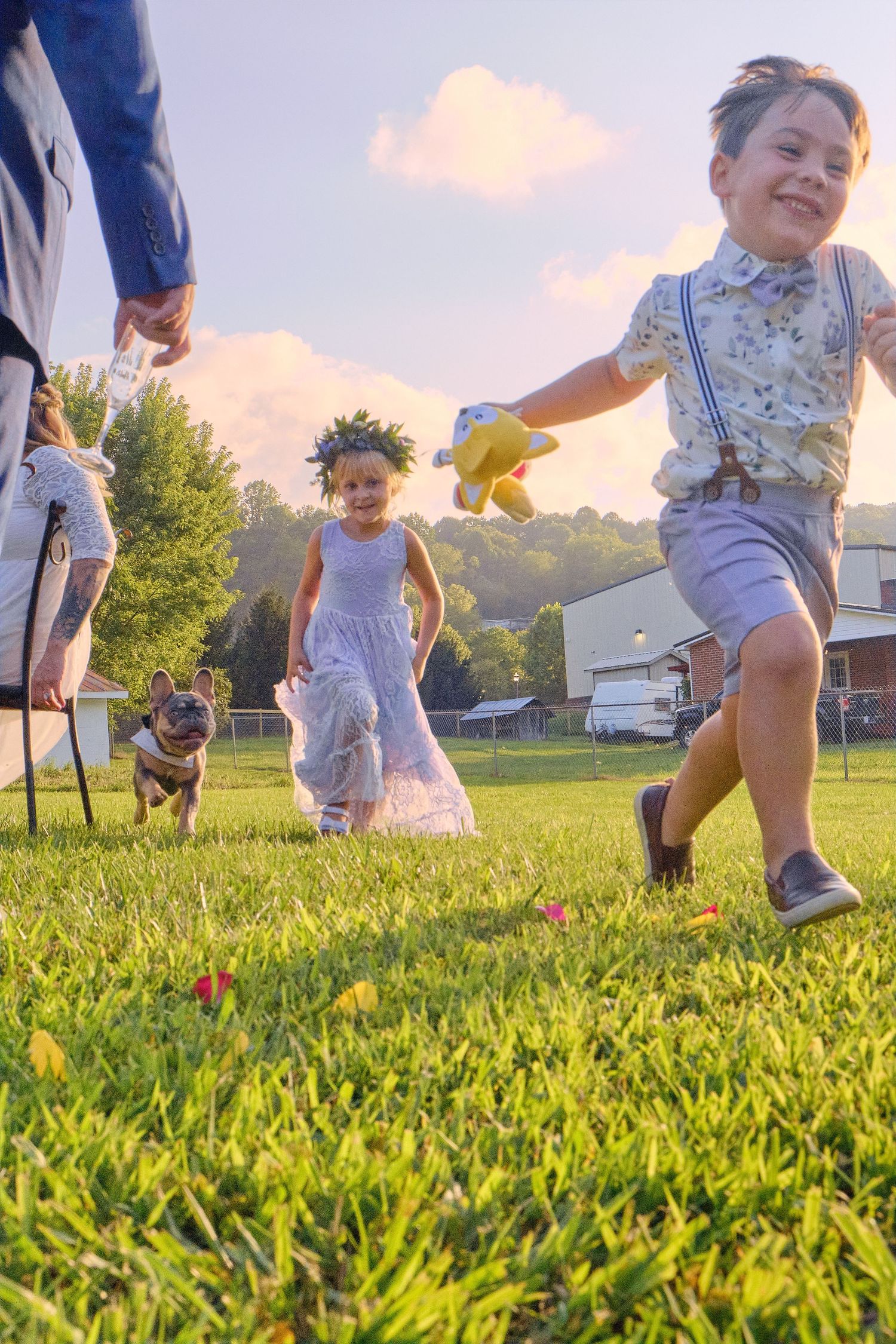 Children playing and running in a grassy field during golden hour sunset.