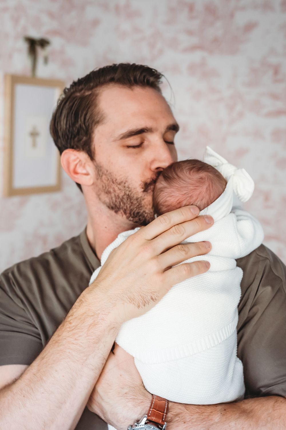 A tender moment between parent and newborn baby in white swaddle in New Haven, CT.
