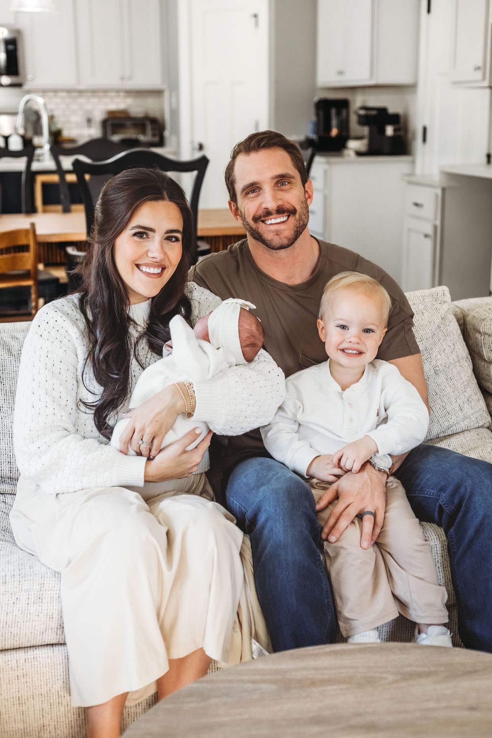Family relaxing together on a cozy grey couch in their bright kitchen in New Haven, CT.