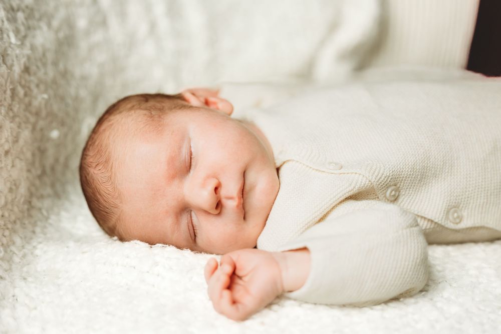 Sleeping newborn baby swaddled in soft white blankets New Haven, CT.