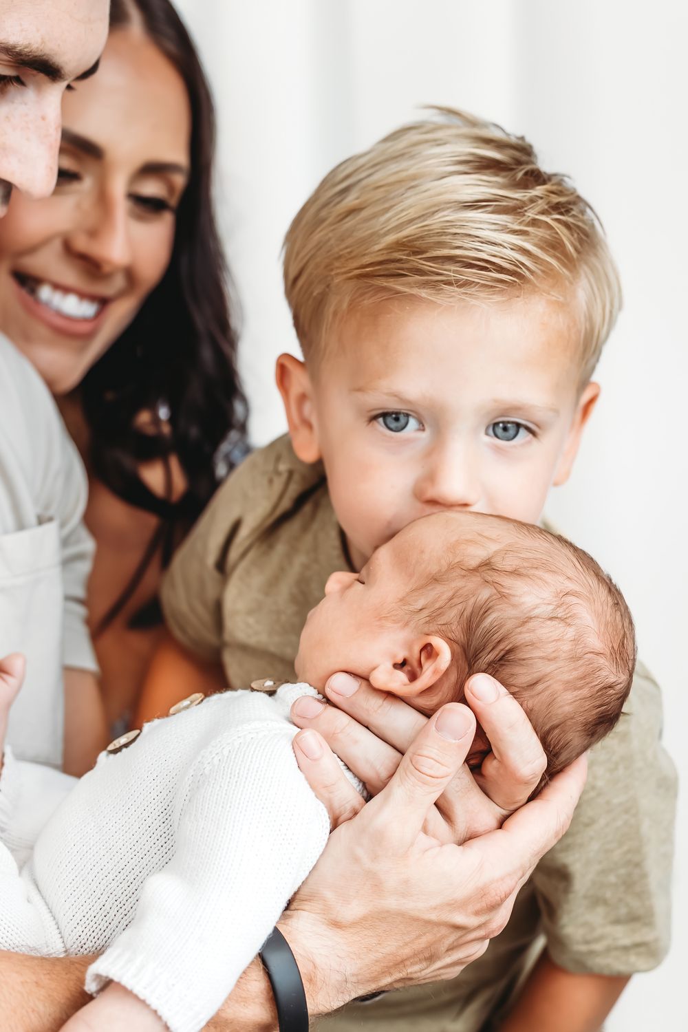 Siblings sharing a sweet moment with newborn baby in white in New Haven, CT.
