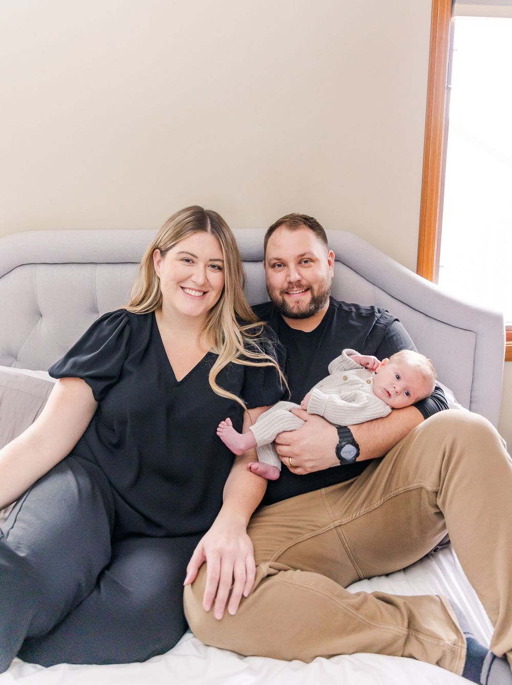 A family relaxes together on a gray couch in a bright living room interior.