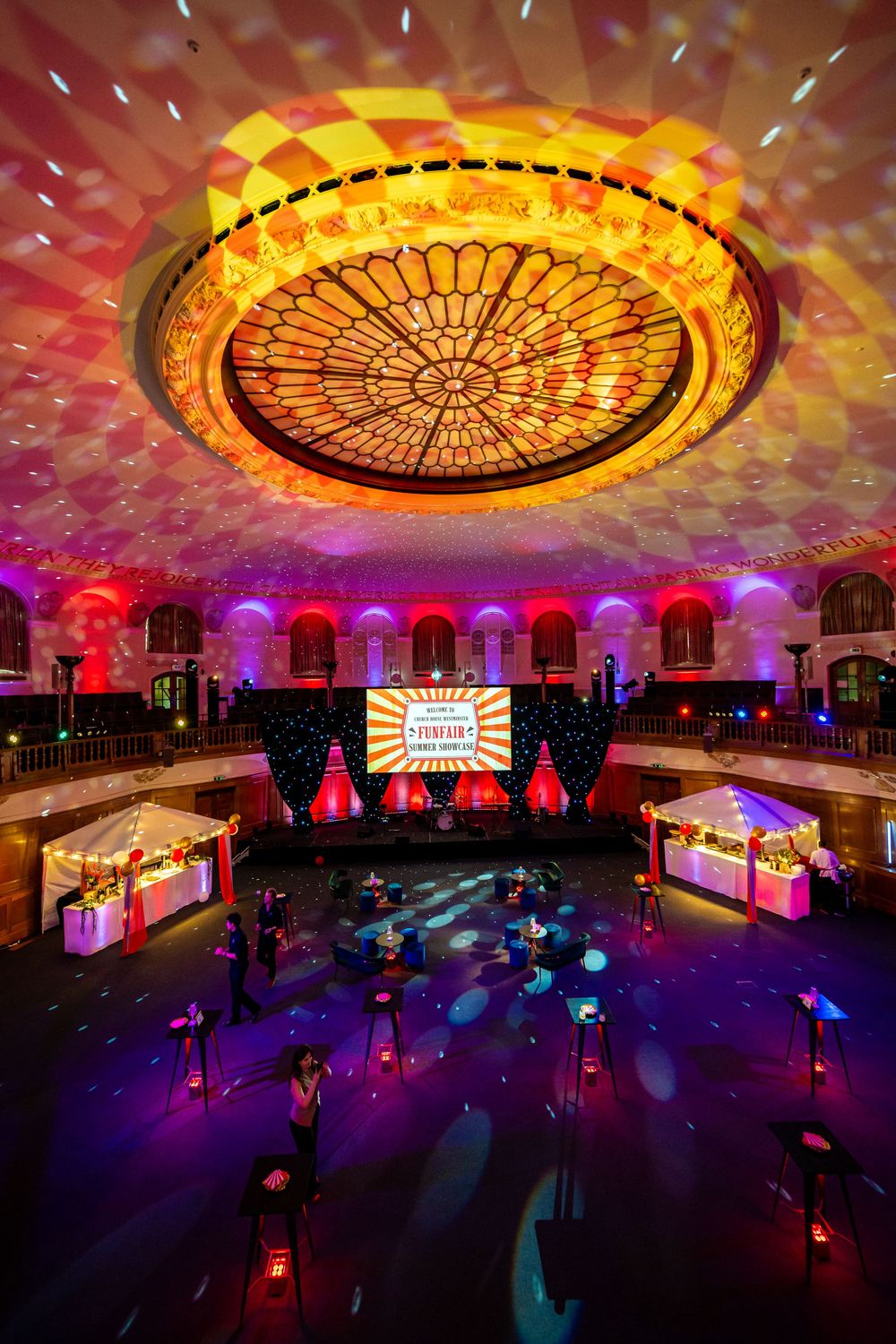 Illuminated dome ceiling casting colorful patterns over a darkened event space with dramatic lighting.