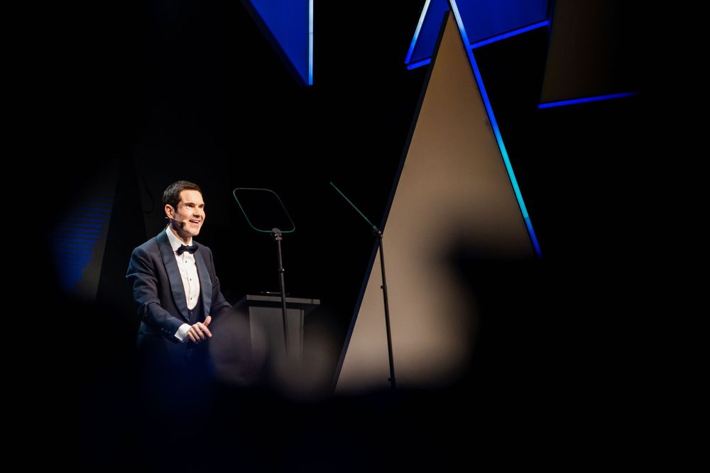 Dramatic spotlight illuminates a dark stage with geometric backdrop panels in blue tones.