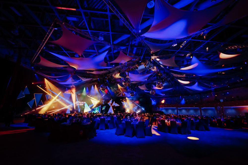 Large event space with dramatic blue lighting and suspended fabric installations creating an ethereal atmosphere.