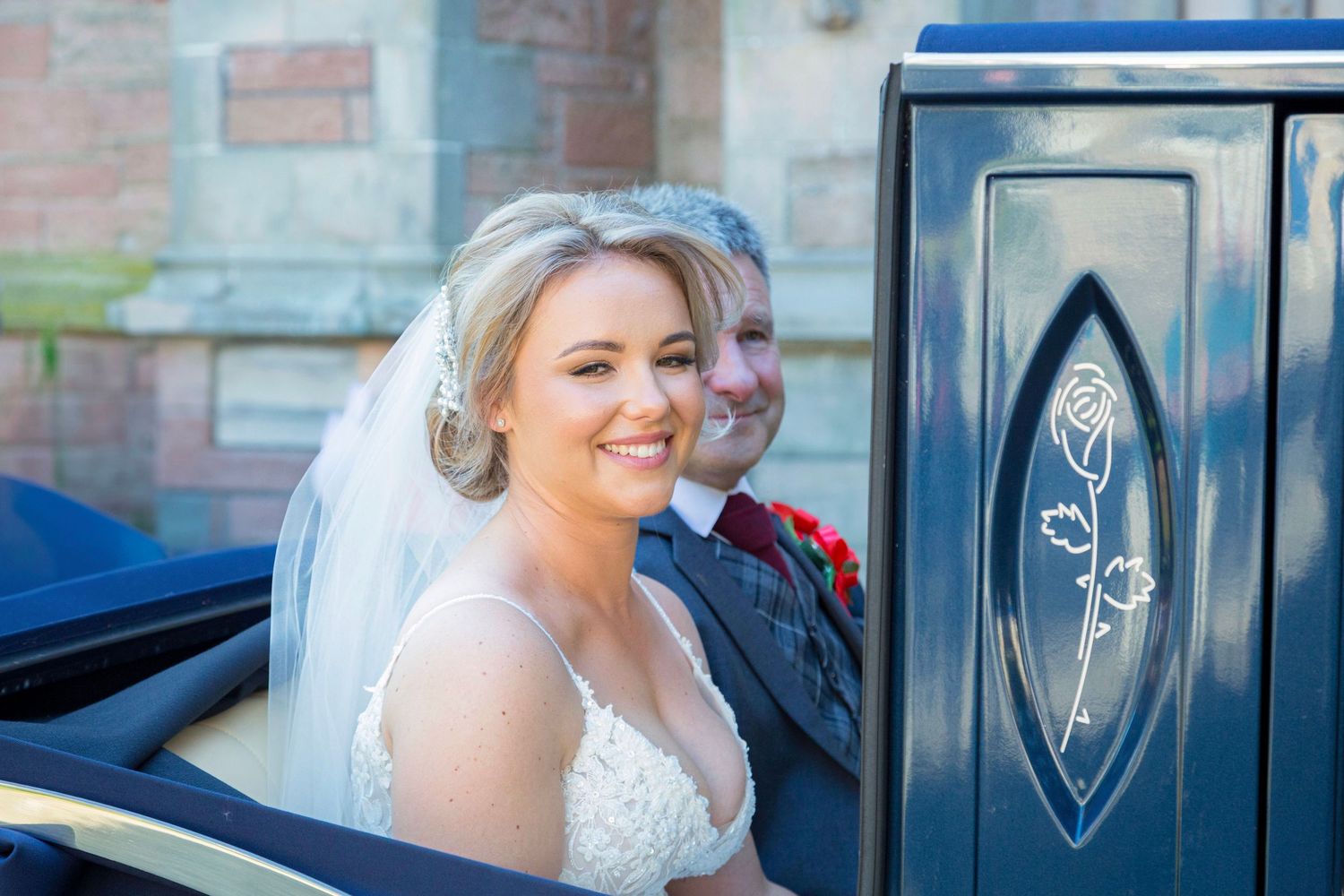 A beautiful bride at inverness cathedral being taken to her wedding by her loving father in a luxury vintage car