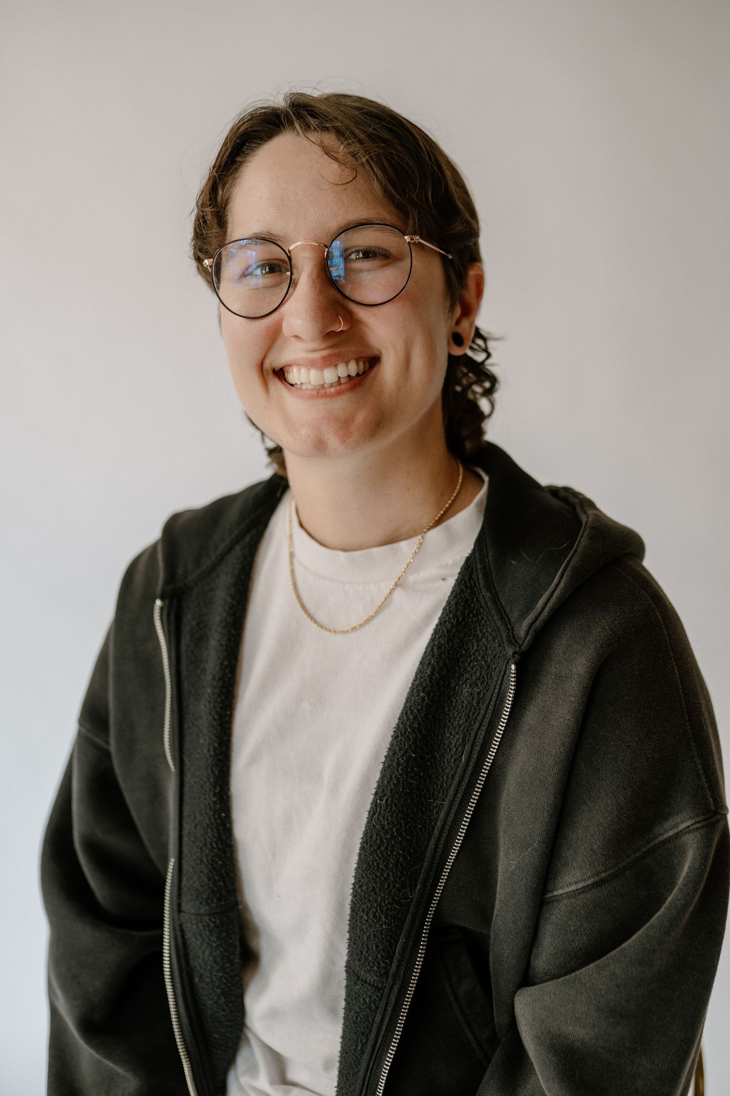 non binary person with glasses posing in a green sweater