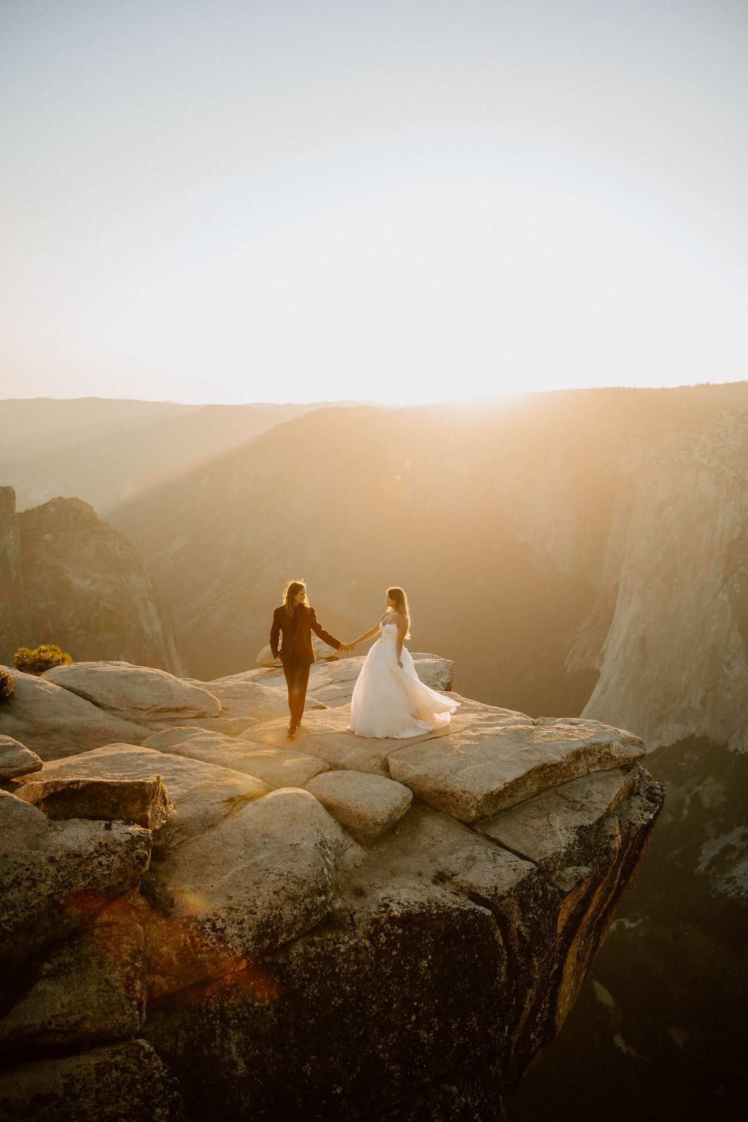 Dramatic sunset silhouette of couple on mountain cliff edge at Yosemite.