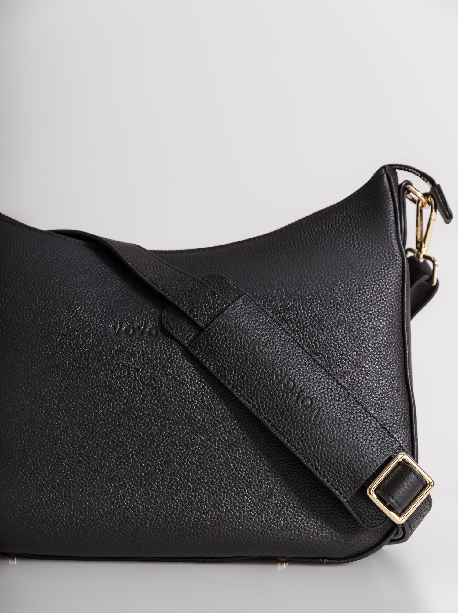 Black pebbled leather crossbody bag with gold-tone hardware and adjustable strap, featuring embossed logo detail.