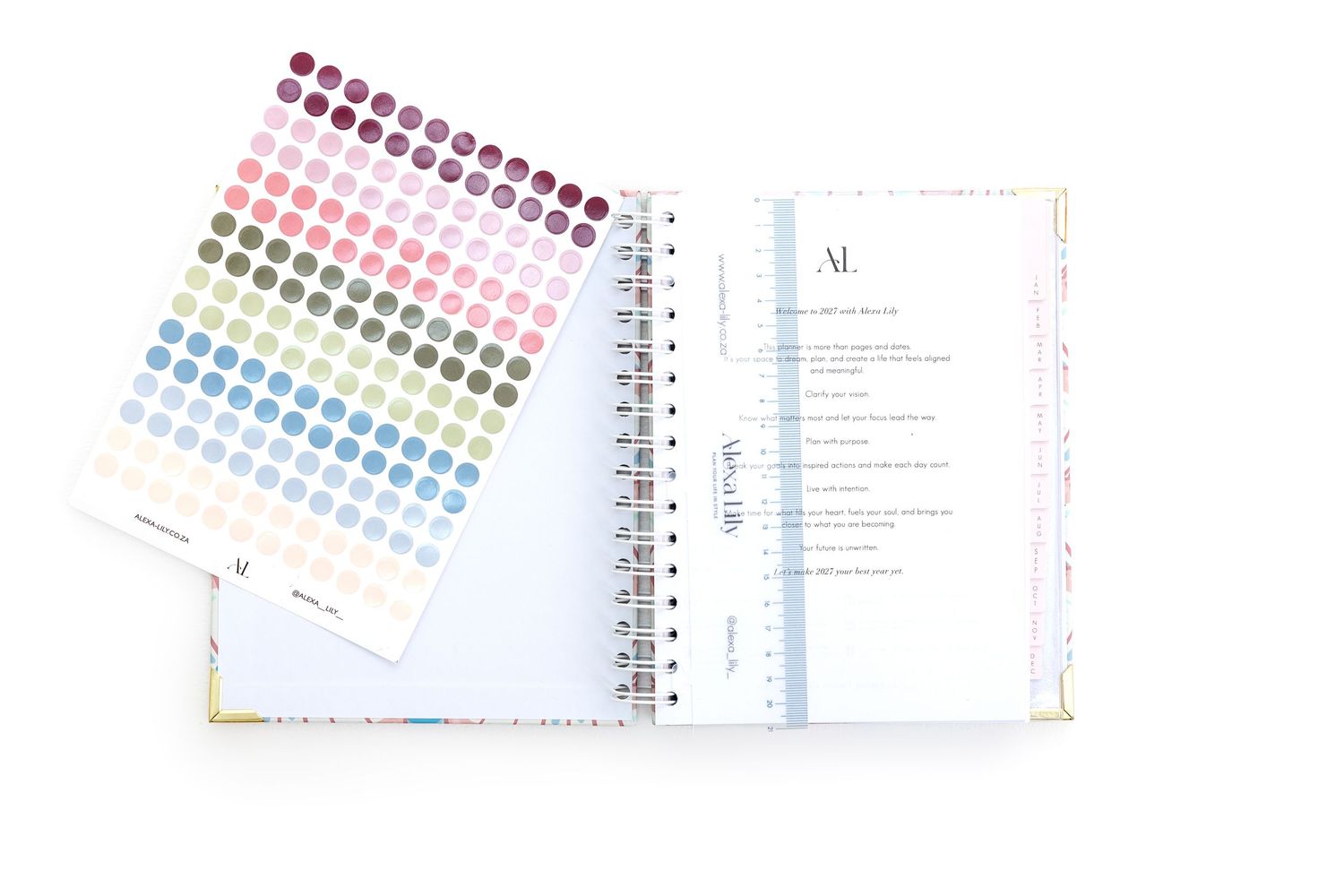 Spiral-bound planner open to a weekly layout beside a colorful dot sticker sheet for organization.