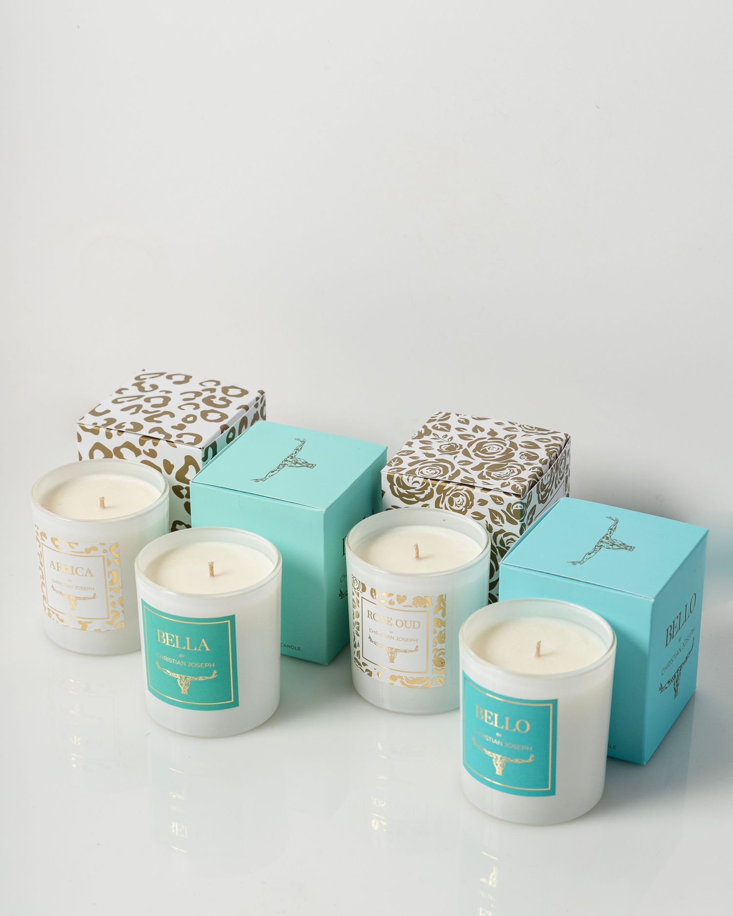 A series of elegant white candles in glass containers with turquoise boxes featuring gold accents arranged in a row.